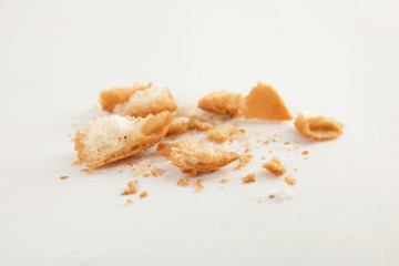 Scattered bread crumbs on white background, closeup