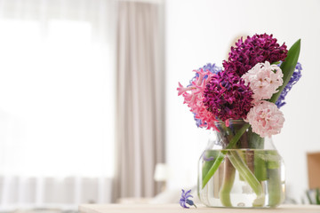 Beautiful hyacinths in glass vase on table indoors, space for text. Spring flowers