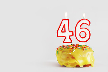 Forty six years anniversary. Birthday cupcake with white burning candles with red border in the form of number Forty six. Light gray background with copy space
