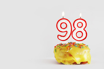 Ninety eight years anniversary. Birthday cupcake with white burning candles with red border in the...