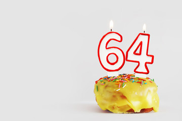Sixty four years anniversary. Birthday cupcake with white burning candles with red border in the form of 64 number. Light gray background with copy space