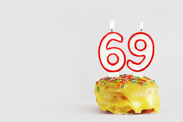 Sixty nine years anniversary. Birthday cupcake with white burning candles with red border in the form of 69 number. Light gray background with copy space