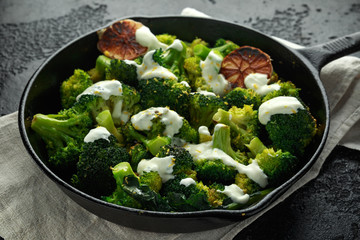 Fried broccoli with garlic yogurt and lemon zest in cast iron skillet, frying pan