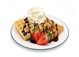  fresh belgian waffles topped with chocolate sauce, strawberries and whipped cream on a plate isolated on white background