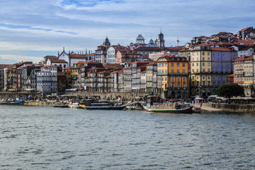 Fototapeta na wymiar View of the old town along the Douro River in Porto, Portugal. Characteristic buildings and boats along the shore. No people.