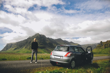 Man standing next to his car in the mountains