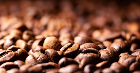 Pile of coffee beans texture, close up, dark background, shallow depth of field