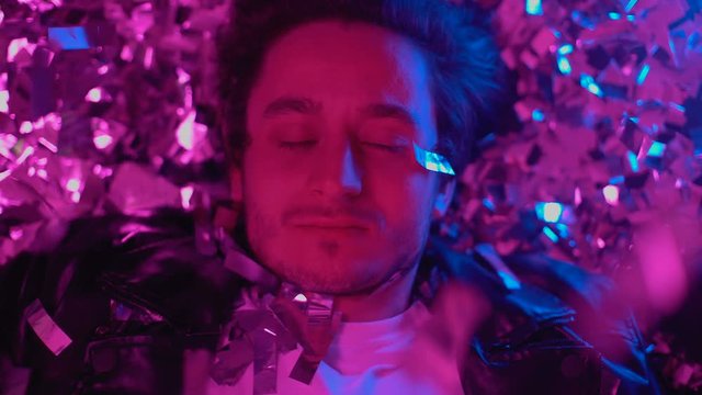 Guy taking ecstasy tablet to enjoy rush effect on floor covered with confetti