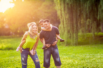 Fototapeta premium Funny time – Happy Parents playing with their children in the park.