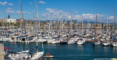 Fototapeta na wymiar Sailing boats with blue and cloudy sky in harbor Barcelona 