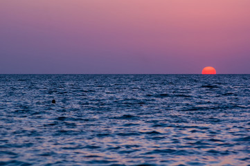 Amazing sea sunset on the pebble beach, the sun, waves, clouds