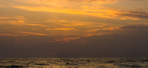 Amazing sea sunset on the pebble beach, the sun, waves, clouds