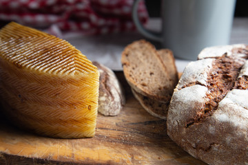 sliced rye bread on a rustic table with a plaid cloth a cheese and a mug