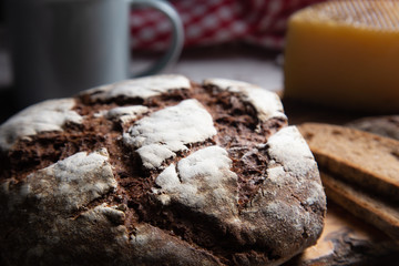 sliced rye bread on a rustic table with a plaid cloth a cheese and a mug