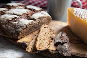 sliced rye bread on a rustic table with a plaid cloth a cheese and a mug