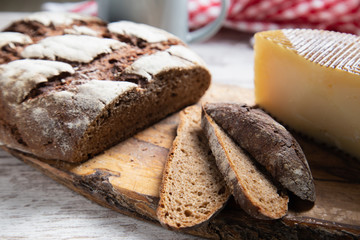 sliced rye bread on a rustic table with a plaid cloth a cheese and a mug