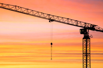 The silhouette of crane on the background of beautiful scarlet sunrise or sunset with cloudy sky...