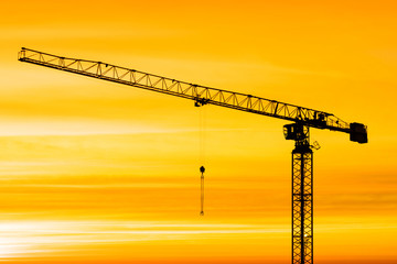 The silhouette of crane on the background of beautiful scarlet sunrise or sunset with cloudy sky...