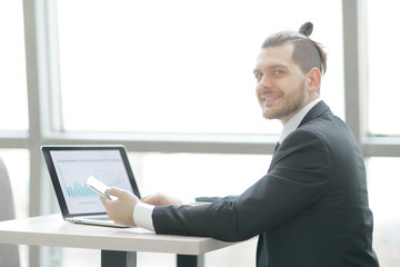 casual businessman working with mobile and laptop in modern office