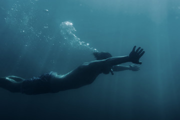 Fototapeta na wymiar Young man swimming underwater, breaststroke.