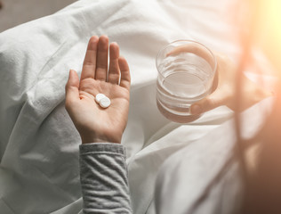 Ill woman in hospital bed take pills