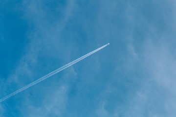 Blue sky with light clouds and traces of flying aircraft