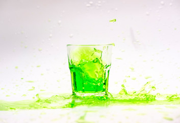 Green cocktail splash in glass isolated on white background
