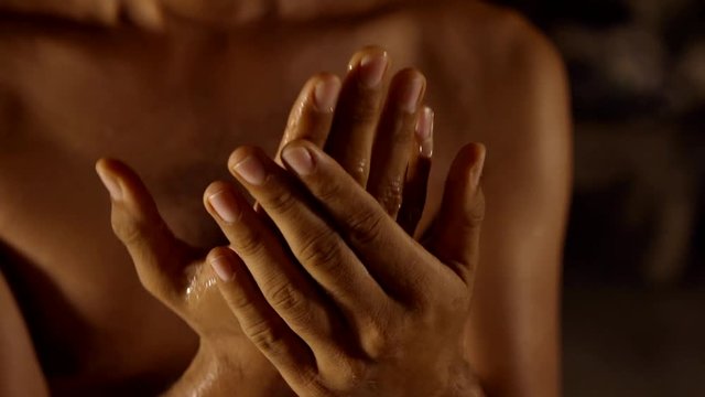 Oriental man lubricates hands coconut oil for massage practice