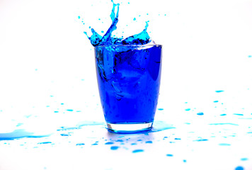 Blue water splashing in glass on white background