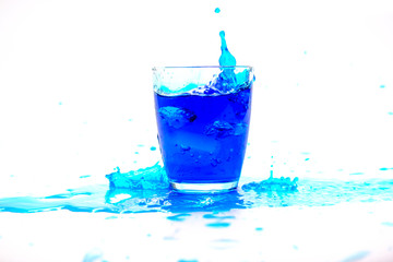 Blue water splashing in glass on white background