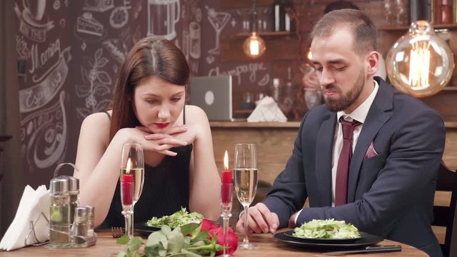 Young woman gets bored on a date and starts to argue with her boyfriend. Tensioned conversation during a dinner date.