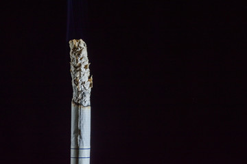 Smoking cigarette on a black background.