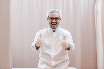 Happy surgeon in sterile uniform showing thumbs up and smiling. Operation went well.