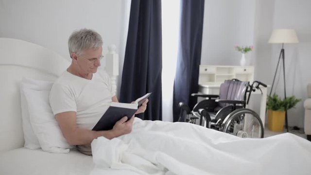 In the Hospital An Adult Man with Gray Hair is Lying on a Bed in His VIP Room.