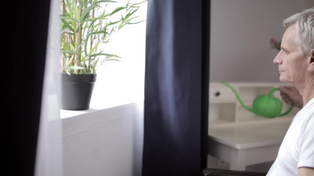 Paraplegic senior man on a wheelchair by the window