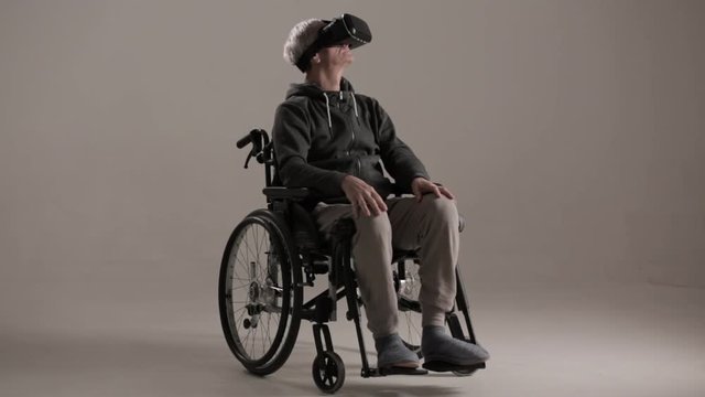 An Adult in a Wheelchair Put on Virtual Reality Glasses.