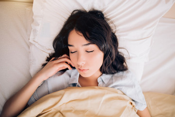 Young beautiful woman sleeping in bed, relaxing in the morning