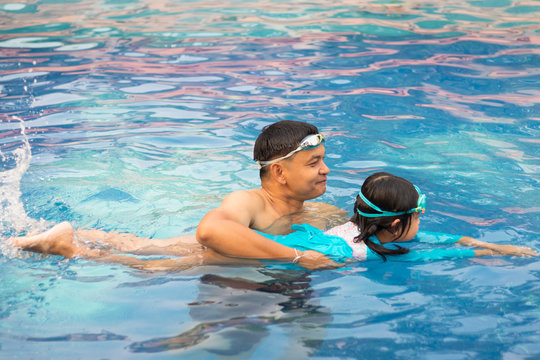 Asian Father Teaching  Daughter To Swim In The Swimming Pool.