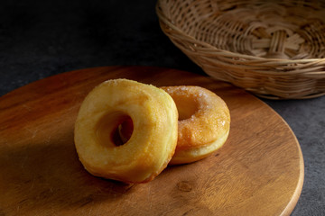 Donuts with sugar on a wooden plate over a dark table background.