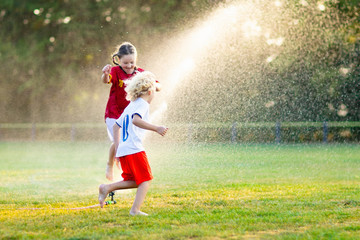 Obraz na płótnie Canvas Kids play with water. Child with garden sprinkler.