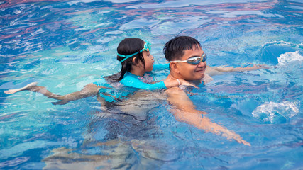 Asian Father and Daughter playing in swimming pool with Girl riding on man.16:9 style