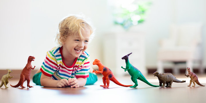 Child playing with toy dinosaurs. Kids toys.