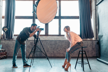 stylish girl bending to the photographer in the room, side view photo