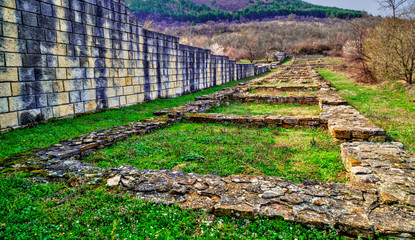 Solid stone wall and ruins of ancient fortress