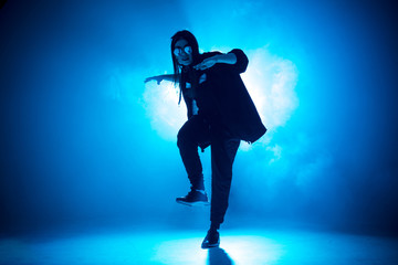 Stylish woman dancing solo on hip hop party. Sunglasses, modern black dance wear, neon lights.