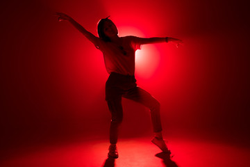 Young woman in casual urban clothes dancing gracefully, moving to hip hop music in the centre of nightclub stage. Laser show in a nightclub. Stage lights. Soffits