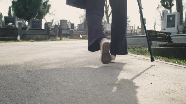 Old woman walking visiting cemetery graves. Shot on Red Camera.