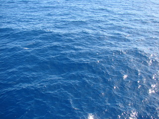 A view from the deck elevation of the ocean liner to the amazing shades of sea blue under the sun rays.