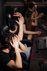 Fototapeta na wymiar Shocked surprised ESport Gamers playing in competitive game in gaming club put their head in his hands in overwhelming joy realising that they have won the game.