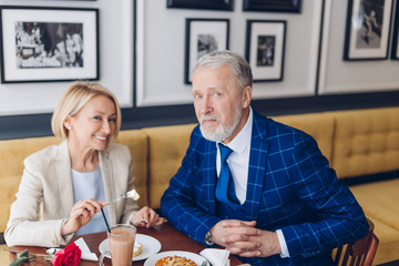 happy mature couple in fashion clothes posing to the camera at the restaurant. close up photo. friendly family spending weekend in the cafe. family tradition